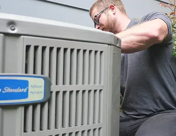 Greers Ferry Heat & Air technician servicing an outdoor air conditioning condenser in Clinton, AR