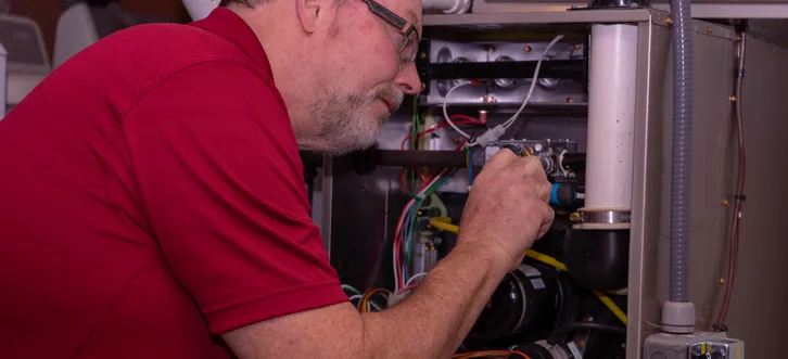 Greers Ferry Heat & Air technician inspecting and diagnosing a gas furnace