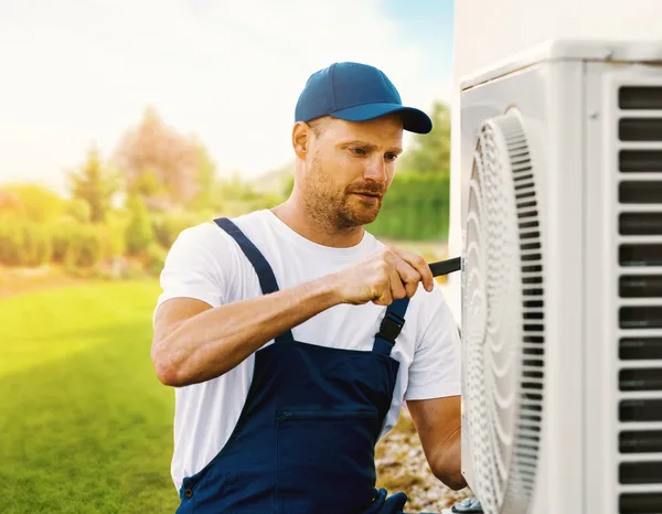 Greers Ferry Heat & Air technician servicing an outdoor heat pump unit