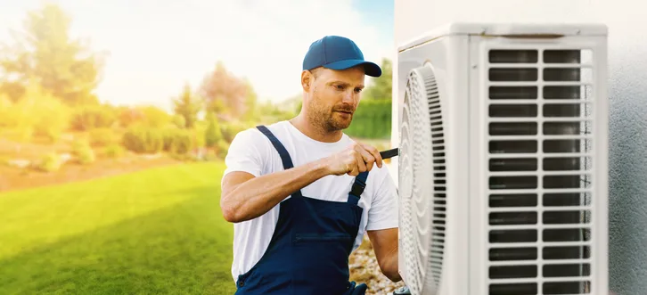 Greers Ferry Heat & Air technician inspecting and tuning up an outdoor heat pump unit