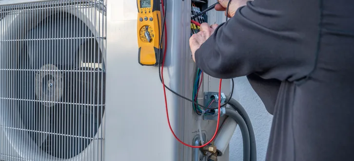 Greers Ferry Heat & Air technician inspecting and diagnosing a ductless mini-split outdoor condenser