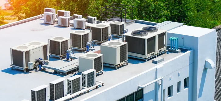 Greers Ferry Heat & Air technician inspecting and cleaning a rooftop package unit condenser coil