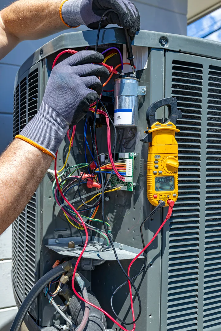 Greers Ferry Heat & Air technician testing an air conditioner's electrical components