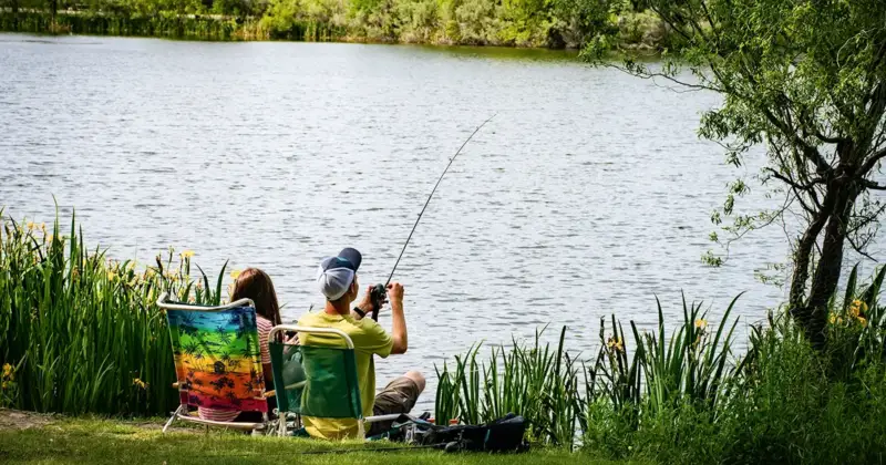 A boy and girl sitting on the bank fishing