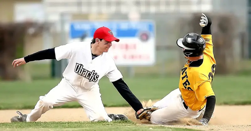 A baseball player slides into base as second basement tries to tag him out