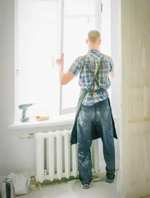 A man is installing new energy efficient windows in an older home.