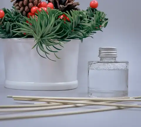 A reed diffuser on the table with a holiday decoration.
