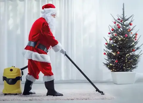Santa Claus is vacuuming the carpet with a HEPA filter