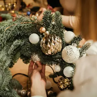 A Christmas wreath and a homeowner preparing to hang it.