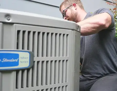 Technician works on a customer's American Standard air conditioning unit.